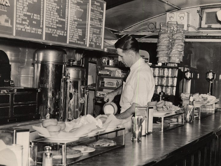 Black and white photo of Don Sr. behind the counter in the 1940's